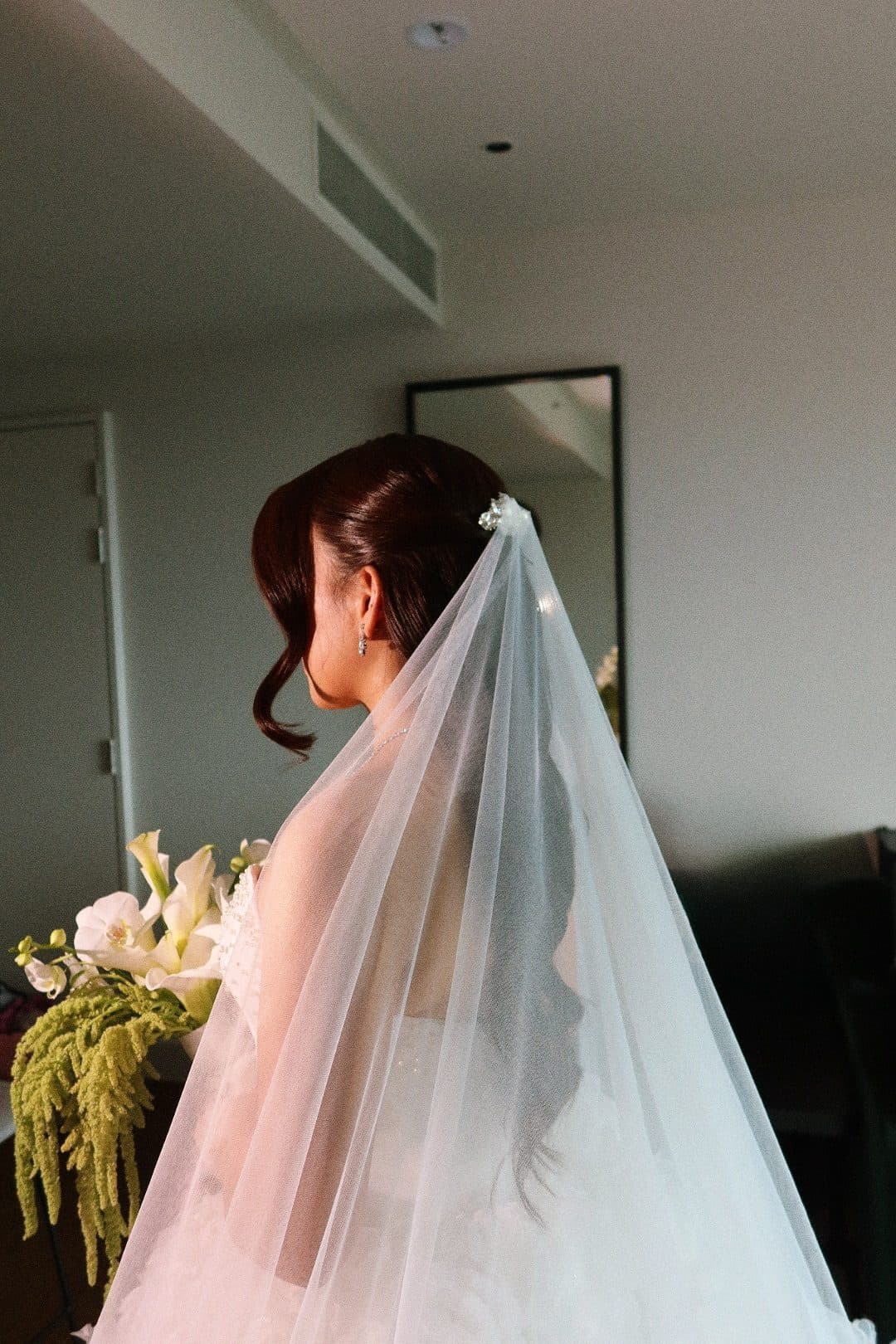 Bridal hair, swept back with soft curls under the veil